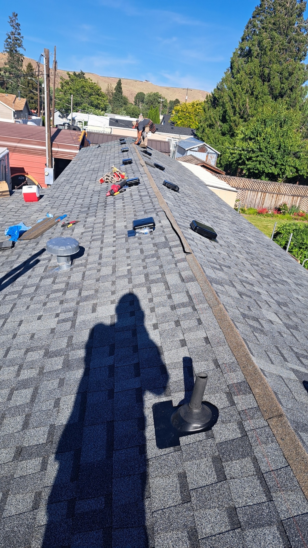 Roofer working on architectural shingle roof installation in progress